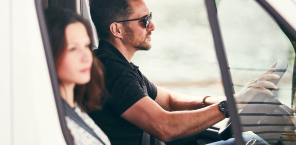 Man en vrouw rijden in Renault Master bedrijfswagen met platform cabine